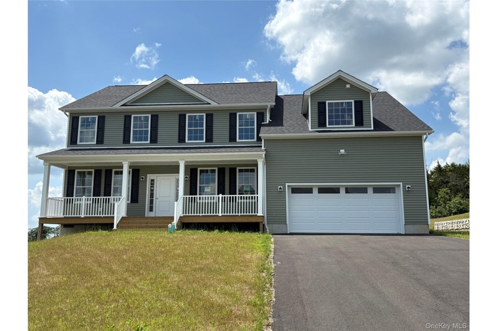 Colonial house featuring driveway, covered porch, a front yard, a garage, and roof with shingles
