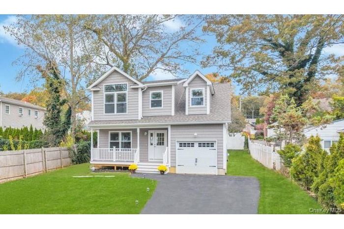 View of front facade featuring covered porch and asphalt driveway