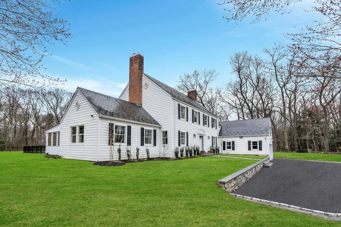 Back of house featuring a yard, a chimney, and a shingled roof