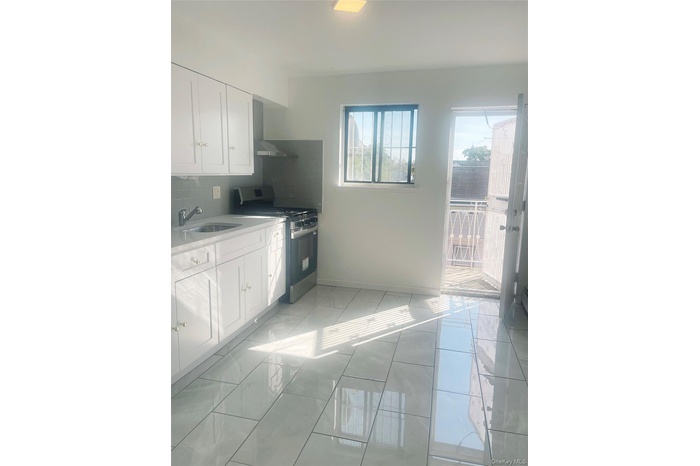 Kitchen with white cabinetry, stainless steel range with gas stovetop, decorative backsplash, and light stone counters
