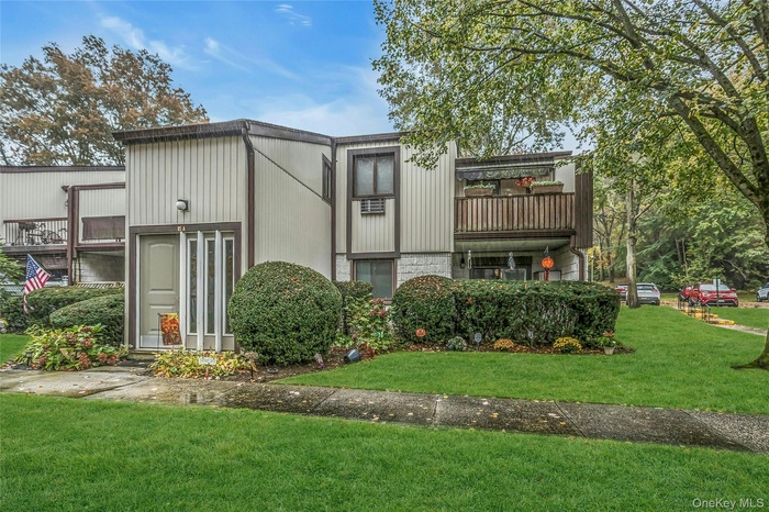 Back of house with a yard and a balcony