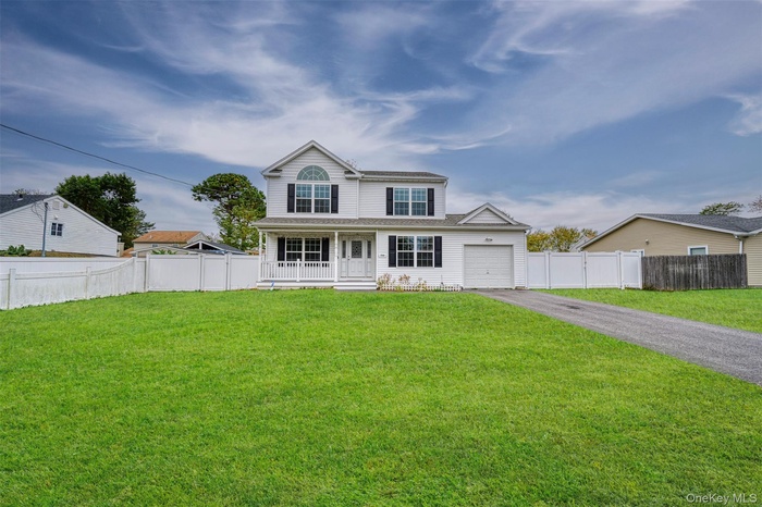 Traditional-style house with asphalt driveway, a porch, and an attached garage