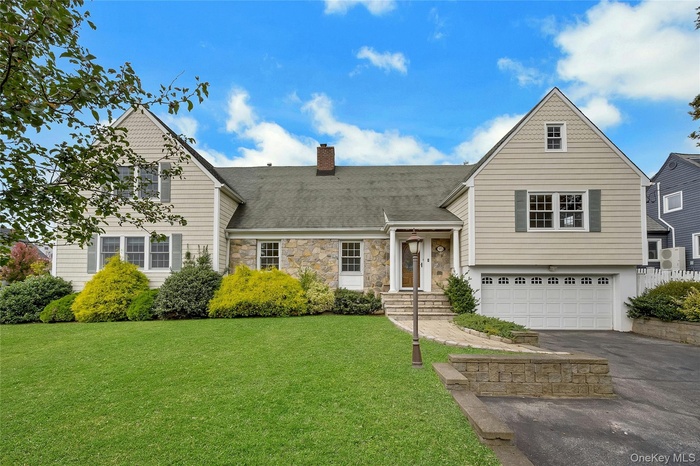 View of front of property with front lawn, stone & vinyl siding, an attached garage