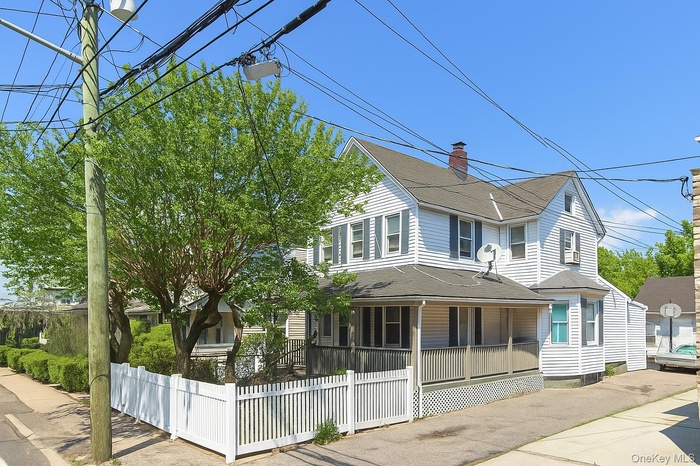 View of front of property with a porch, a fenced front yard, and roof with shingles