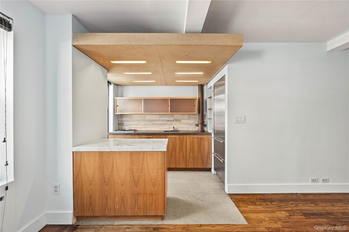 Kitchen with open shelves, tasteful backsplash, baseboards, and light wood-style floors