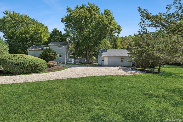 View of green lawn featuring an outdoor structure and driveway