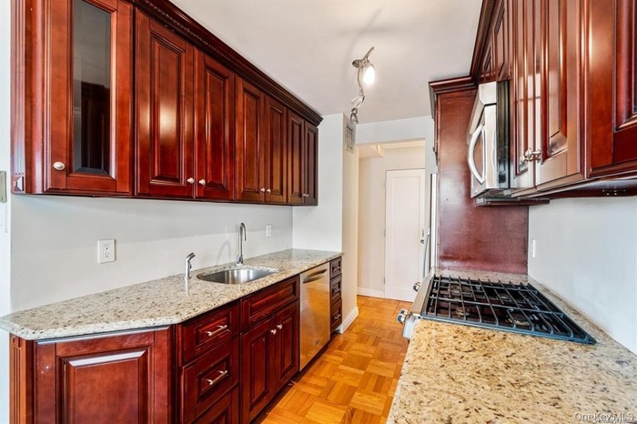 Kitchen featuring dark brown cabinets, light stone countertops, and stainless steel appliances