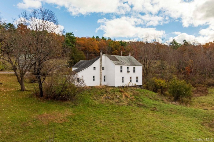 View of home's exterior featuring a chimney, a lawn, and a view of trees