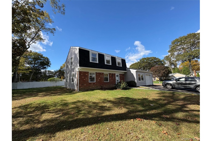 Dutch colonial featuring a gambrel roof, brick siding, a shingled roof, and a garage