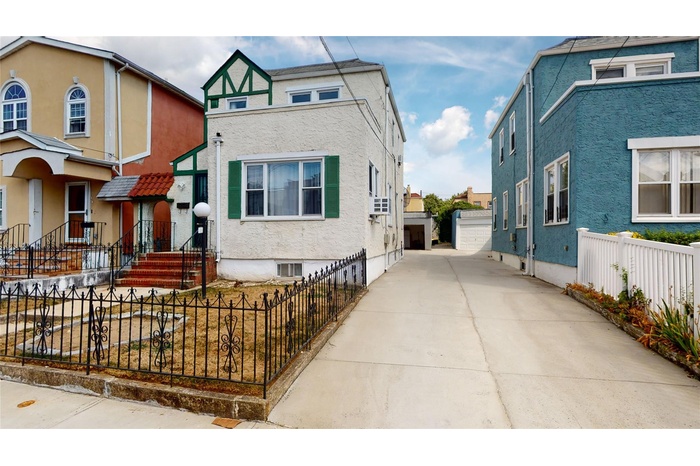 View of front of property featuring stucco siding, an outbuilding, a detached garage, and fence private yard
