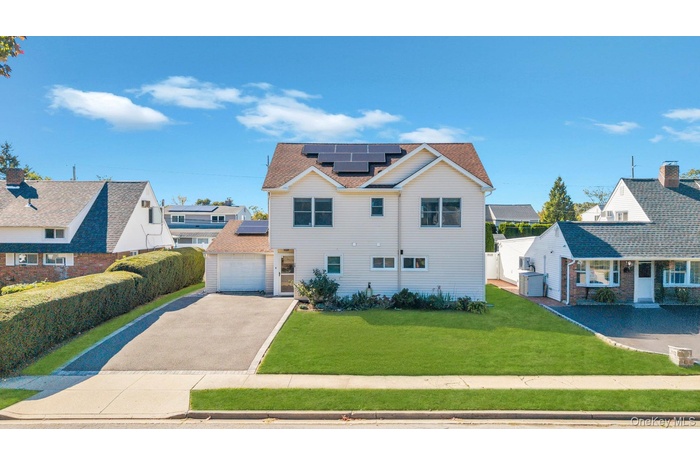 View of front facade with roof mounted solar panels, driveway, and a garage
