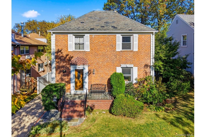 Colonial house featuring brick siding and a front yard