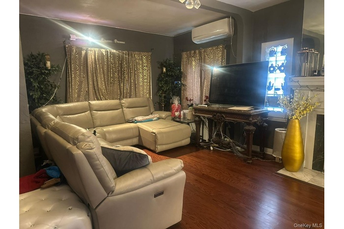 Living area featuring wood finished floors and a wall mounted AC