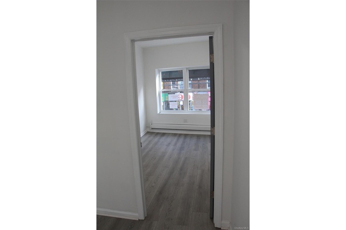 Unfurnished room with wood finished floors and a baseboard heating unit