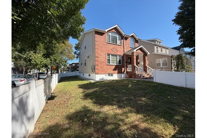 Back of house with a fenced backyard and brick siding
