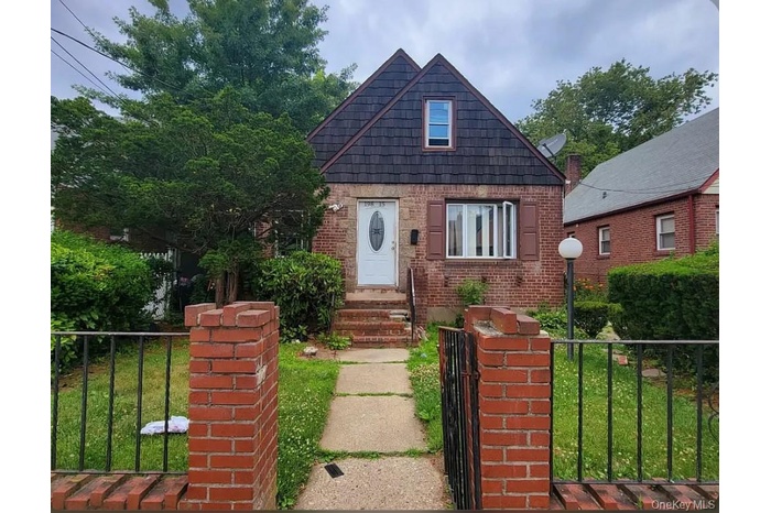 Bungalow with a fenced front yard, brick siding, and a gate