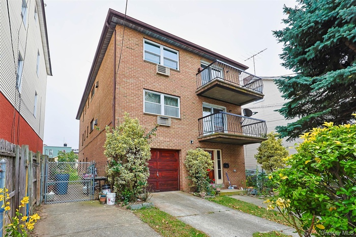 Traditional home featuring a balcony, a gate, brick siding, and concrete driveway