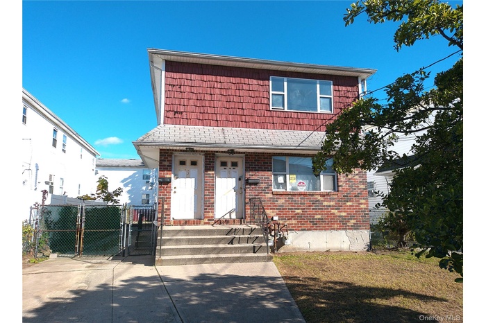 View of front of home featuring a gate and brick siding