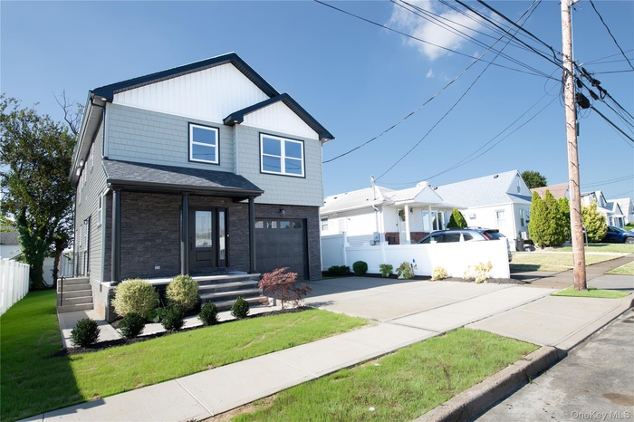 View of front of house with concrete driveway, brick siding, a residential view, and an attached garage