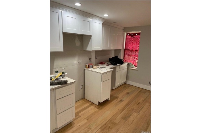 Kitchen featuring white cabinets, light wood-type flooring, recessed lighting, and light stone countertops