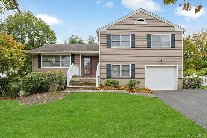 Split level home with an attached garage and asphalt driveway