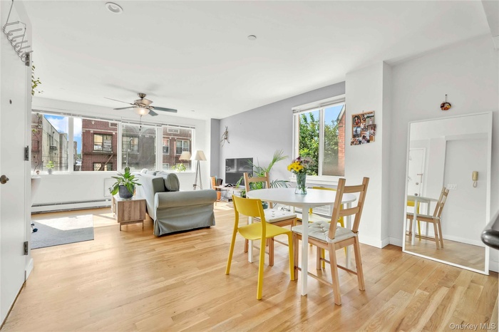 Dining room with light wood finished floors, a baseboard radiator, and ceiling fan