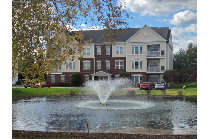 View of front of house featuring brick siding, a water view, and a front yard