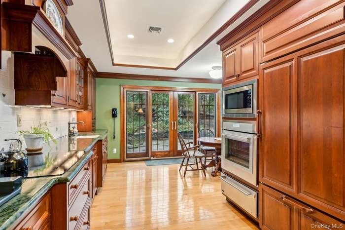 Kitchen featuring tasteful backsplash, a warming drawer, light wood finished floors, built in appliances, and brown cabinets