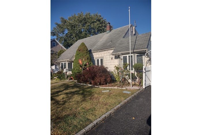 View of front of home featuring a front lawn, a chimney, a shingled roof, cooling unit, and a gate