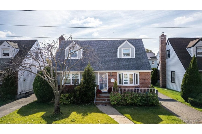 Cape cod home featuring brick siding, a front lawn, and a shingled roof