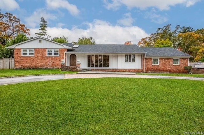 View of front facade featuring a front yard, covered porch, brick siding, and board and batten siding