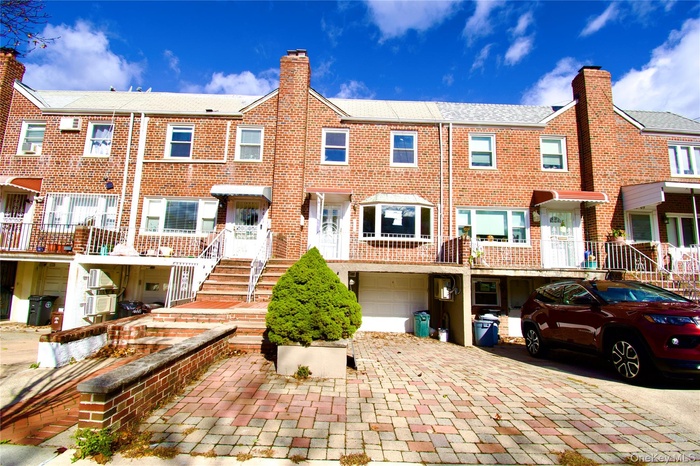 View of front of house with decorative driveway, a chimney, a residential view, a garage, and brick siding