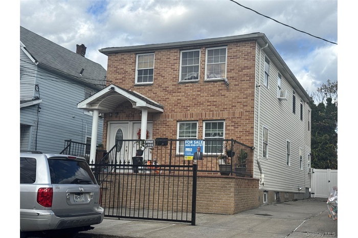 View of front of home with brick siding, a fenced front yard, and a gate