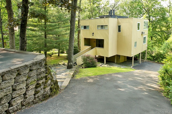 View of front of house featuring stairway and asphalt driveway