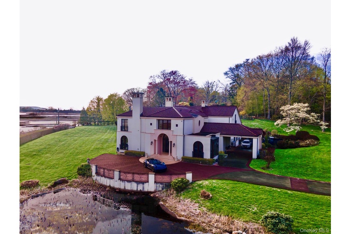 Mediterranean / spanish home with a front yard, a chimney, stucco siding, a wooden deck, and asphalt driveway