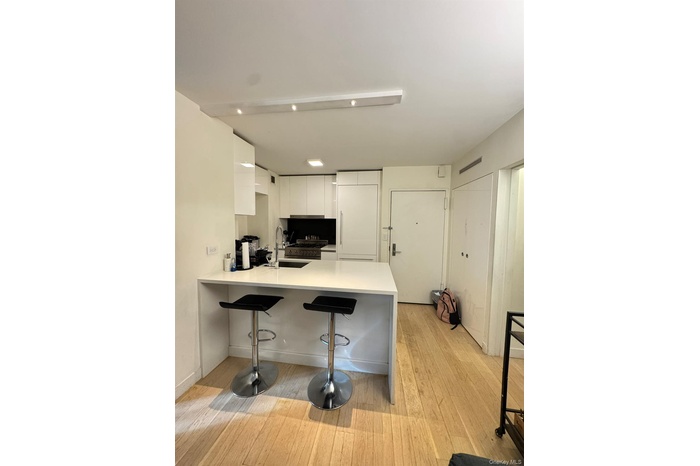 Kitchen featuring a breakfast bar, modern cabinets, white cabinets, a peninsula, and light stone countertops