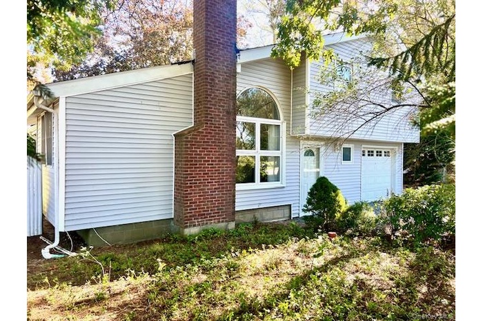 Rear view of house featuring a chimney and a garage