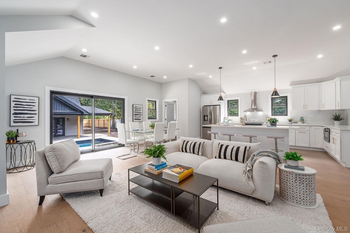 Living area with light wood-style flooring, recessed lighting, and lofted ceiling