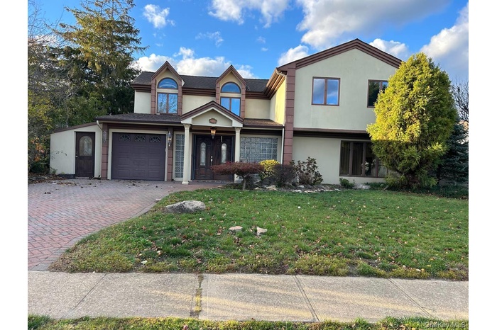 View of front facade with stucco siding, a garage, and a front lawn