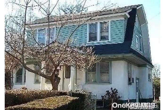View of side of property featuring a gambrel roof and stucco siding