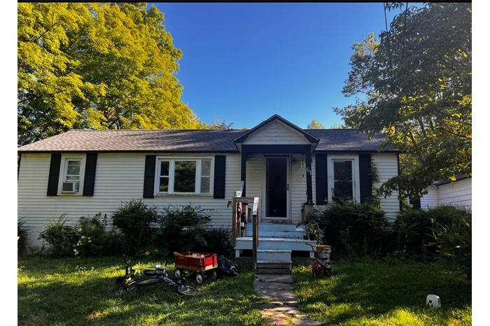 View of front facade featuring cooling unit and a front yard