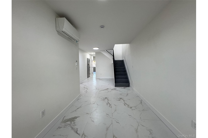 Hallway with stairs, marble finish floors, and an AC wall unit