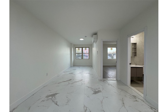 Empty room featuring light marble finish flooring and an AC wall unit