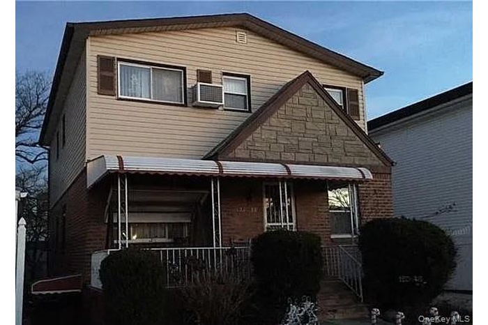 Back of property with covered porch and brick siding
