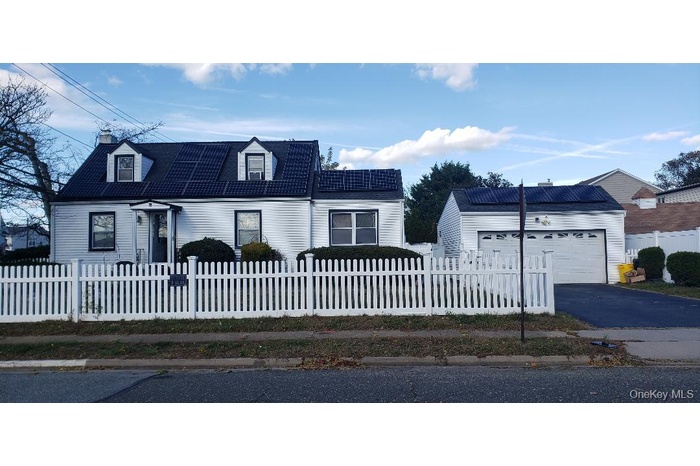View of front of property featuring a fenced front yard, a garage, asphalt driveway, and a chimney