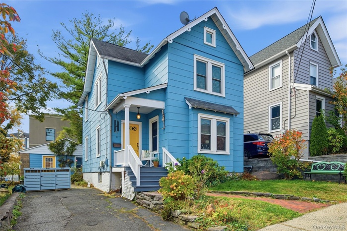 View of front of house featuring roof with shingles, an outdoor structure, and a porch