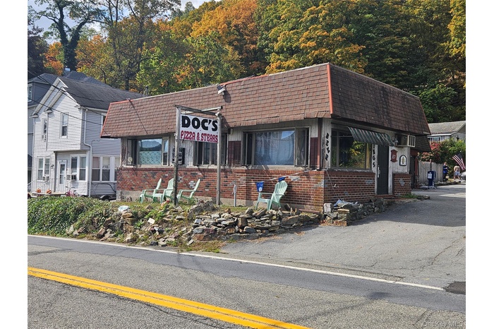 View of front of home featuring brick siding, mansard roof, and roof with shingles