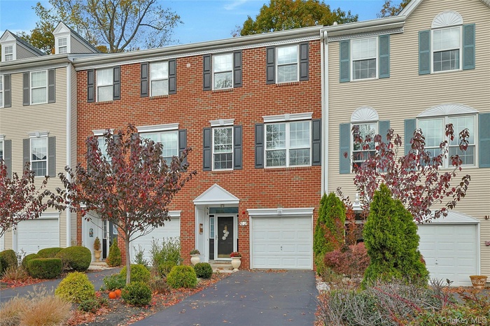 Colonial-style house with brick siding, driveway, and a garage