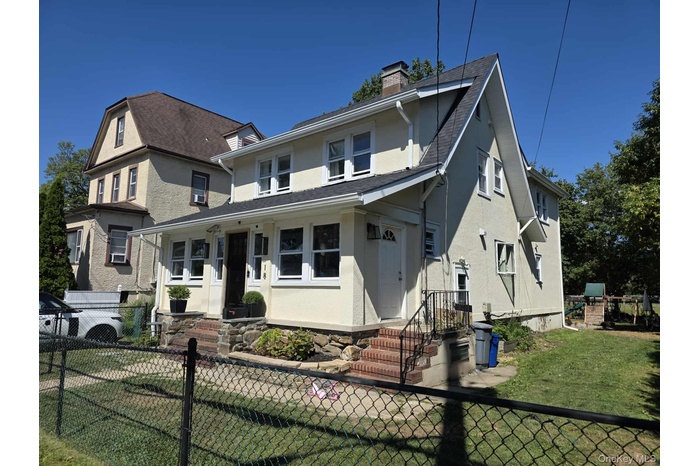 View of front facade with a fenced front yard, stucco siding, and a chimney