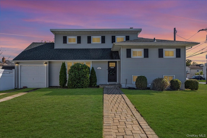 Tri-level home with roof with shingles and a garage